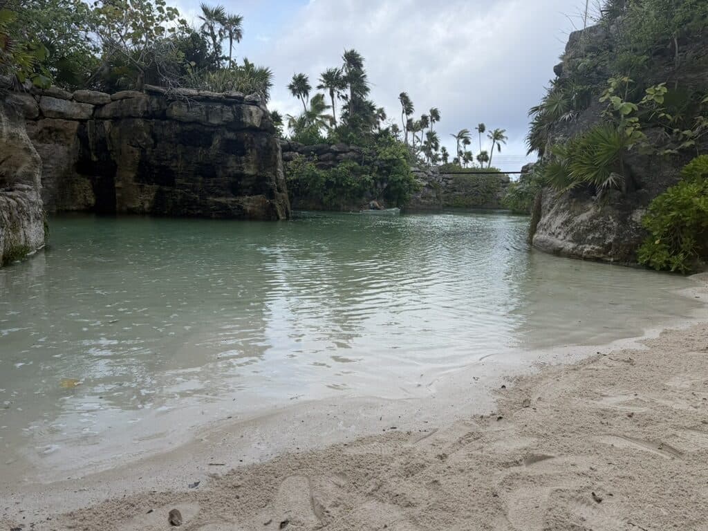 The shallow man-made river beach at Hotel Xcaret México, sand meeting clear green water