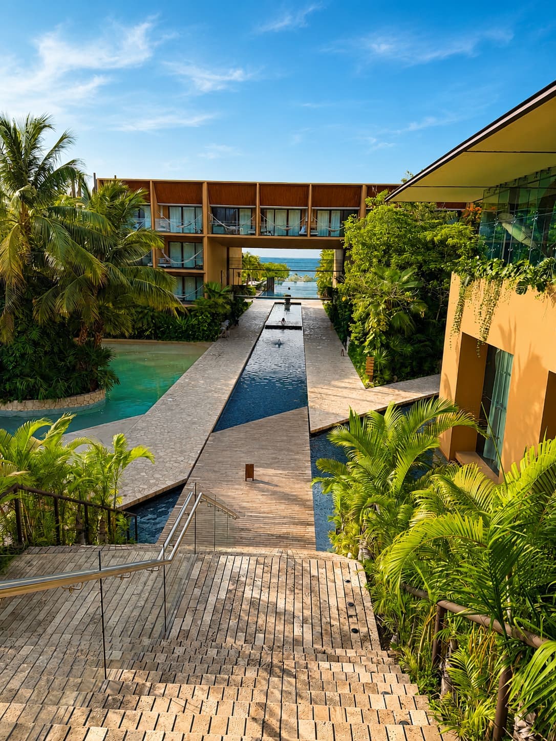 The view from Lobby 1 at Hotel Xcaret México: stairs dropping to the long water feature, with the ocean framed straight ahead