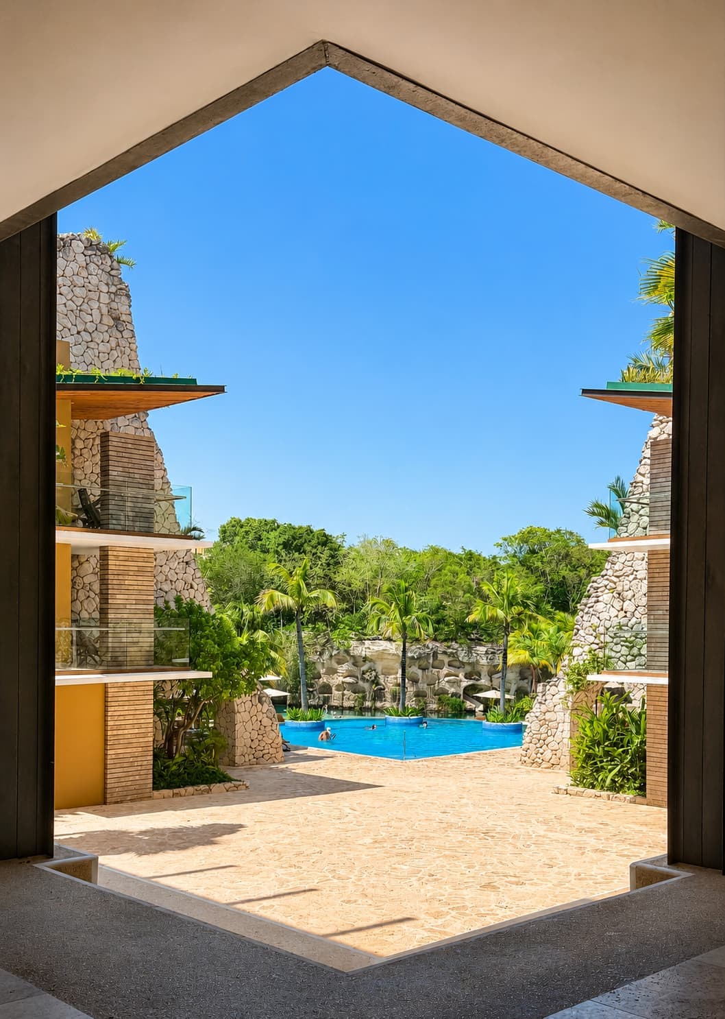 A pool framed through one of the stone portals at Hotel Xcaret México
