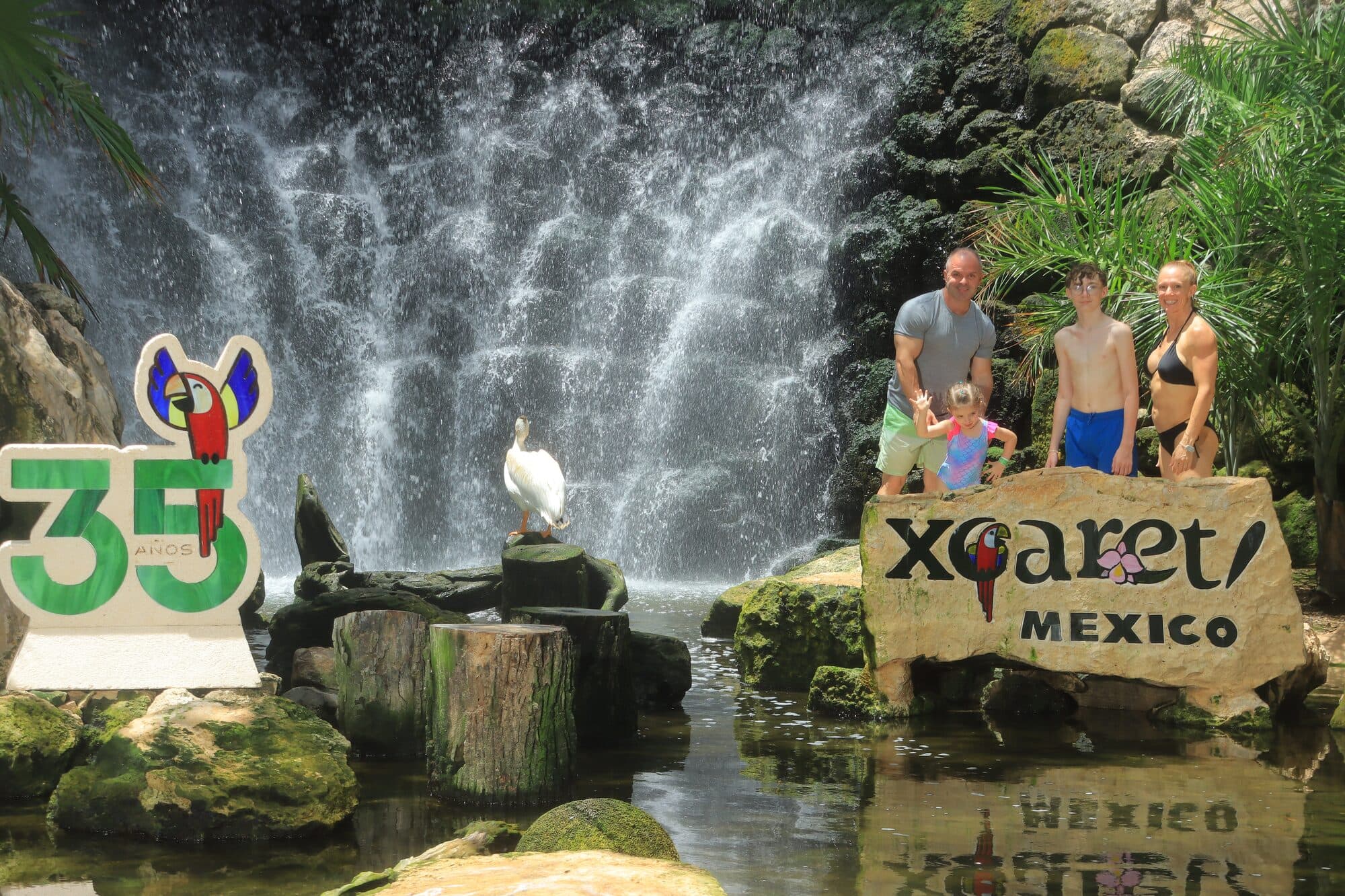 The Xcaret Mexico park sign beside a waterfall, where ticket tiers are checked at entry