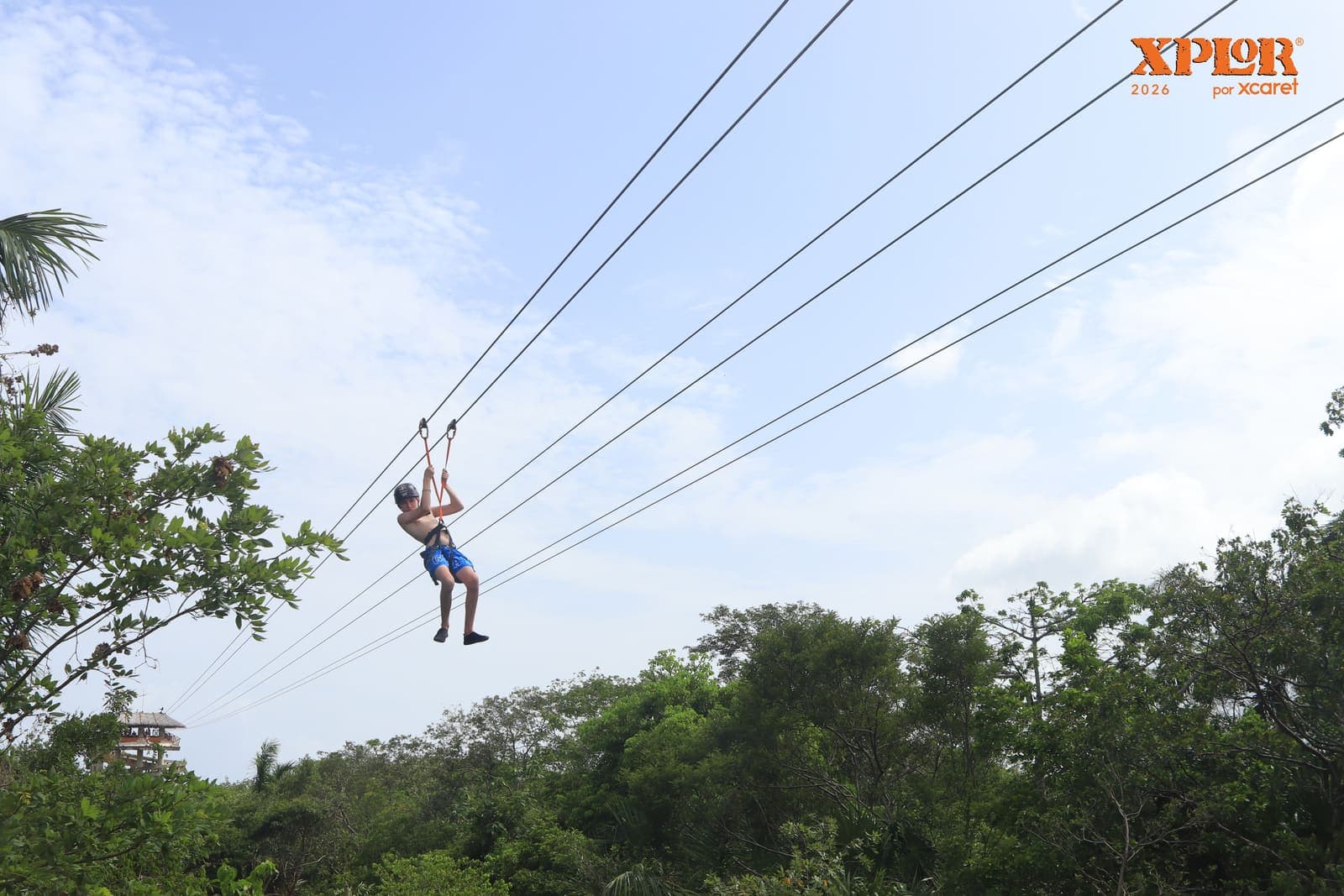 A zipliner crossing the jungle canopy against open sky at Xplor park, Riviera Maya