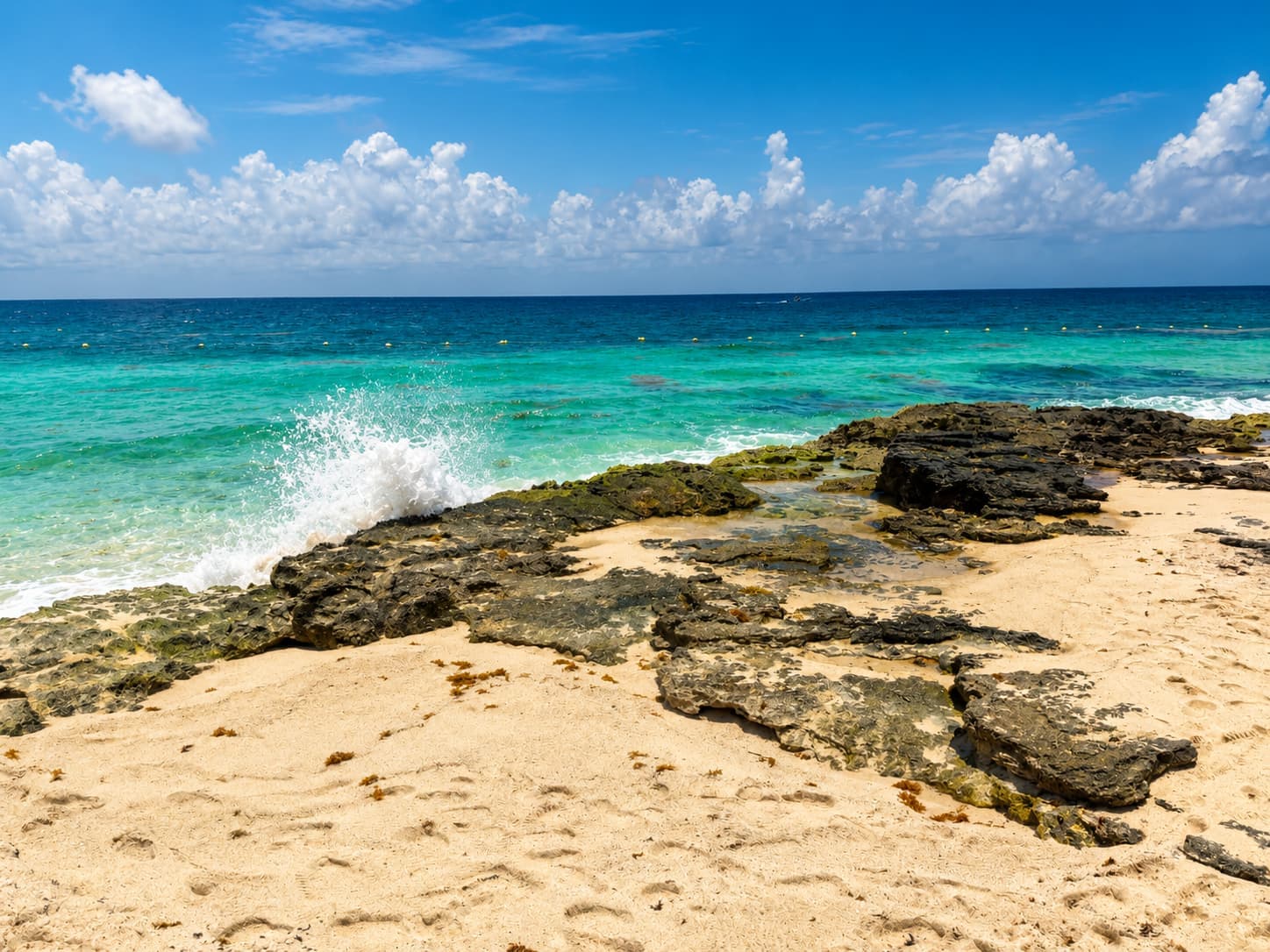 The rocky ocean edge at Hotel Xcaret México in July, turquoise water beyond